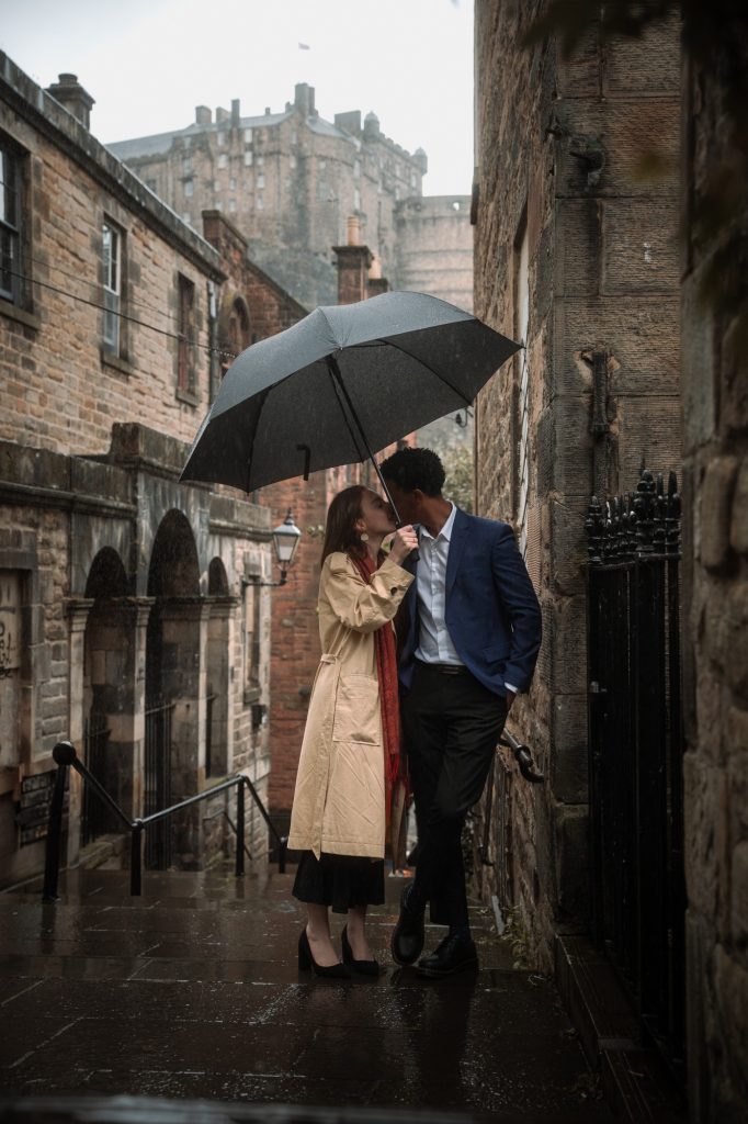 Couple sharing an umbrella on a rainy day in the Vennel, below Edinburgh Castle